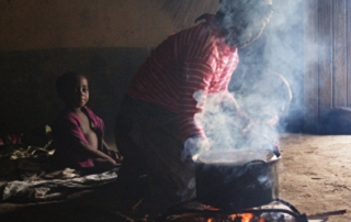 woman cooking indoors with child nearby