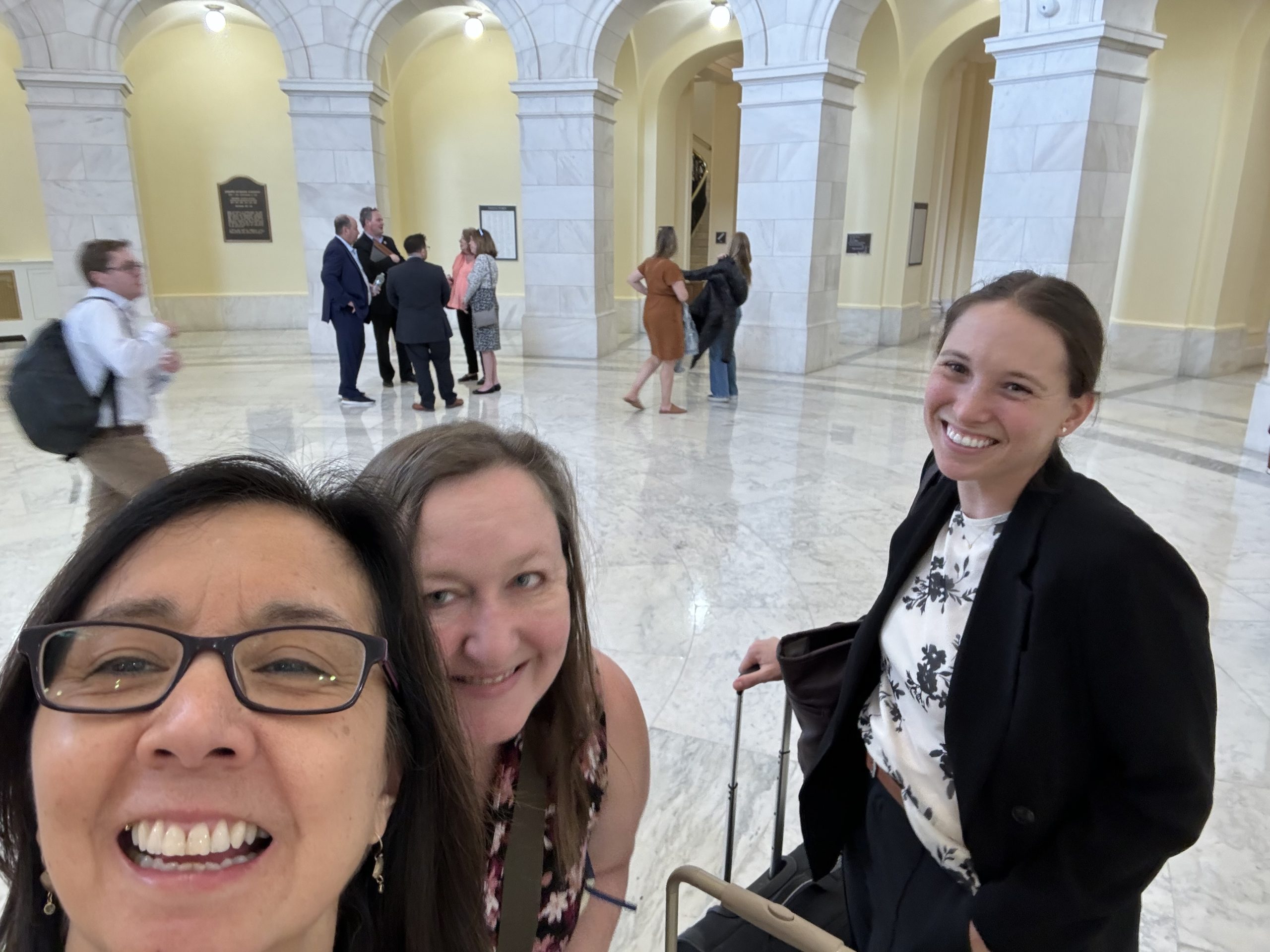 LisaKarenLogan_congressOffices Three women, Lisa Miller, Karen Bales, and Logan Savidge standing inside a marble rotunda smiling at the camera